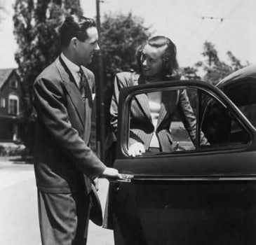 black and white photo of man holding open car door for wife